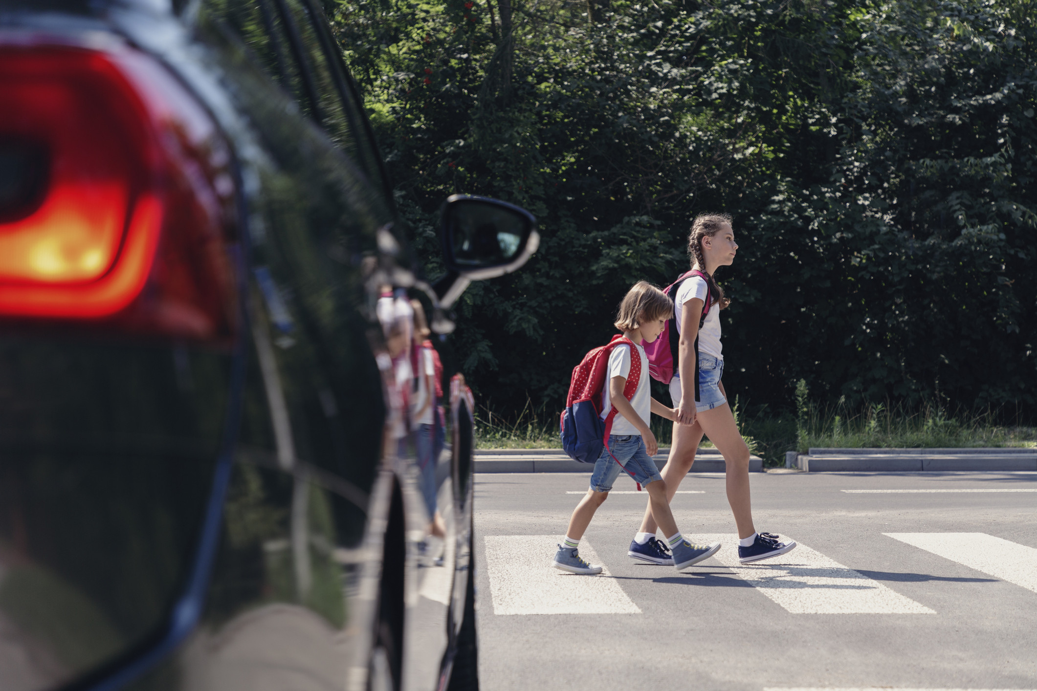 A sister and brother walk across the street